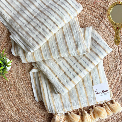 Ivory mulmul cotton saree striped in fine gold and silver zari, folded flat