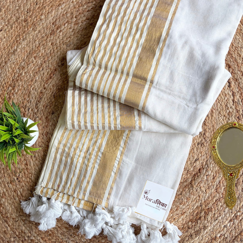 Shwet white mulmul cotton saree with gold zari stripes and woven gold border, folded flat